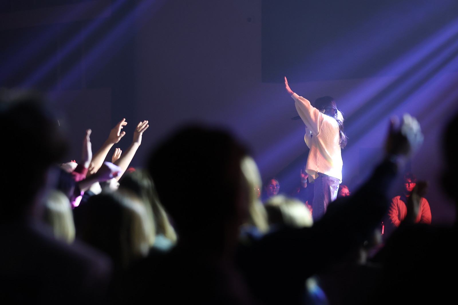 Worship leader with hand raised over a crowd of students
